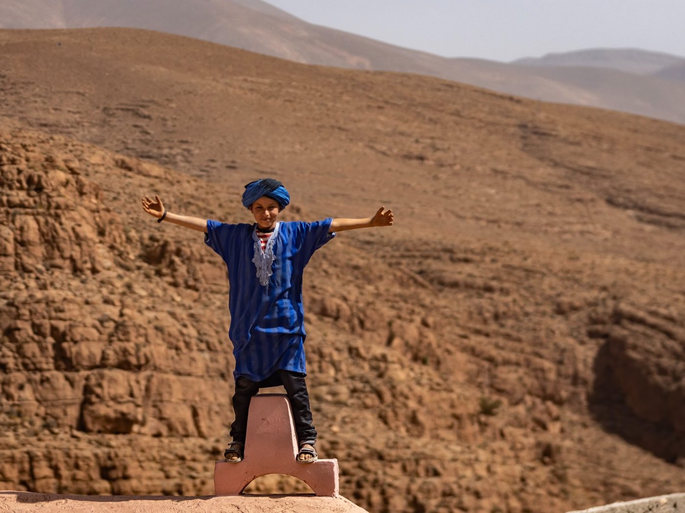 A child in blue clothing standing in a desert landscape